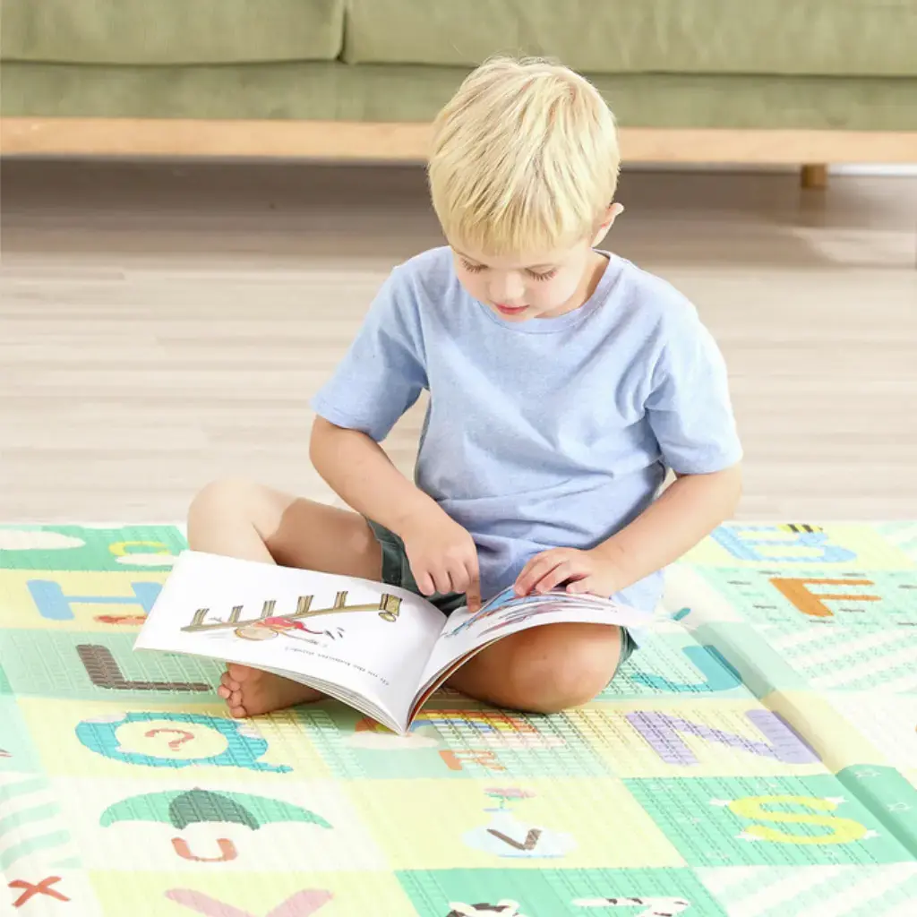 Nino-Leyendo-sobre-Alfombra-Foldable-Alfabeto-Hape.webp