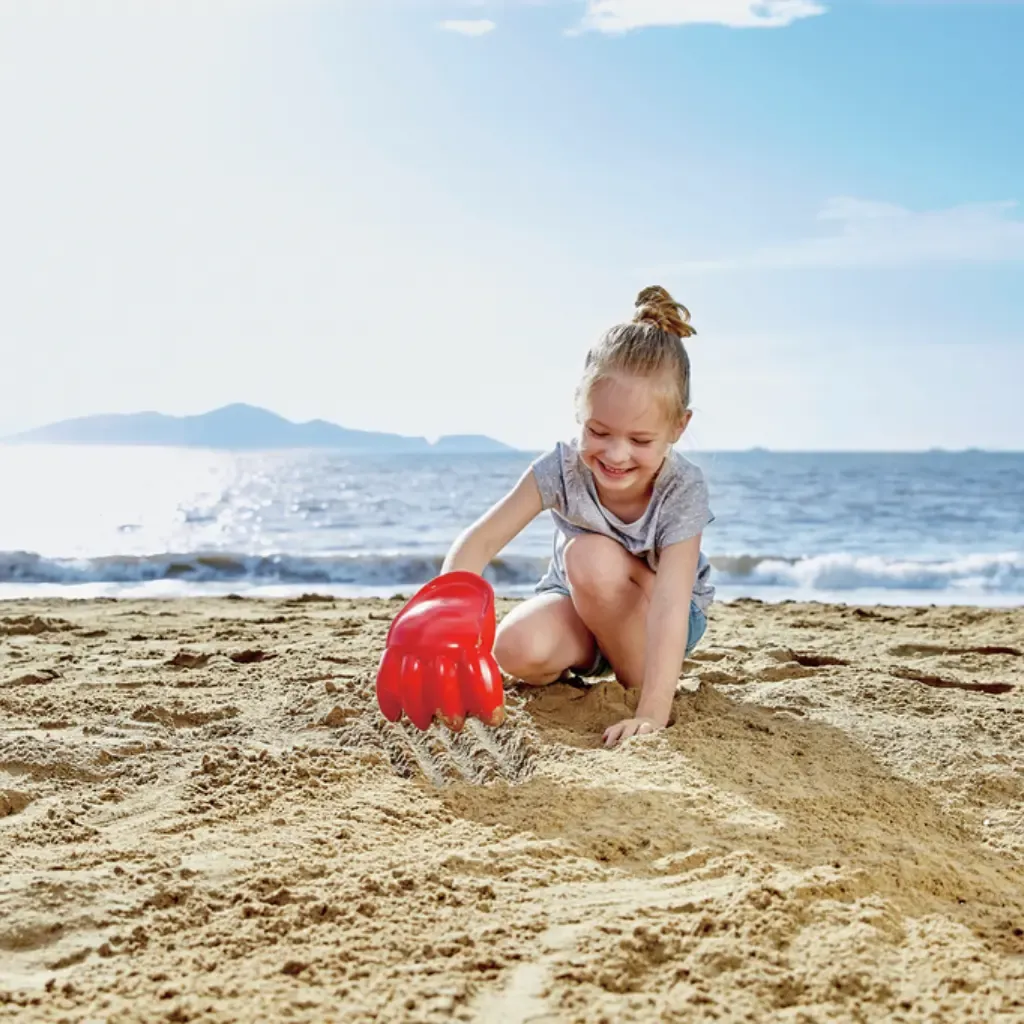 Niña-jugando-en-la-playa-con-Rastrillo-Gigante-Rojo-Hape.webp